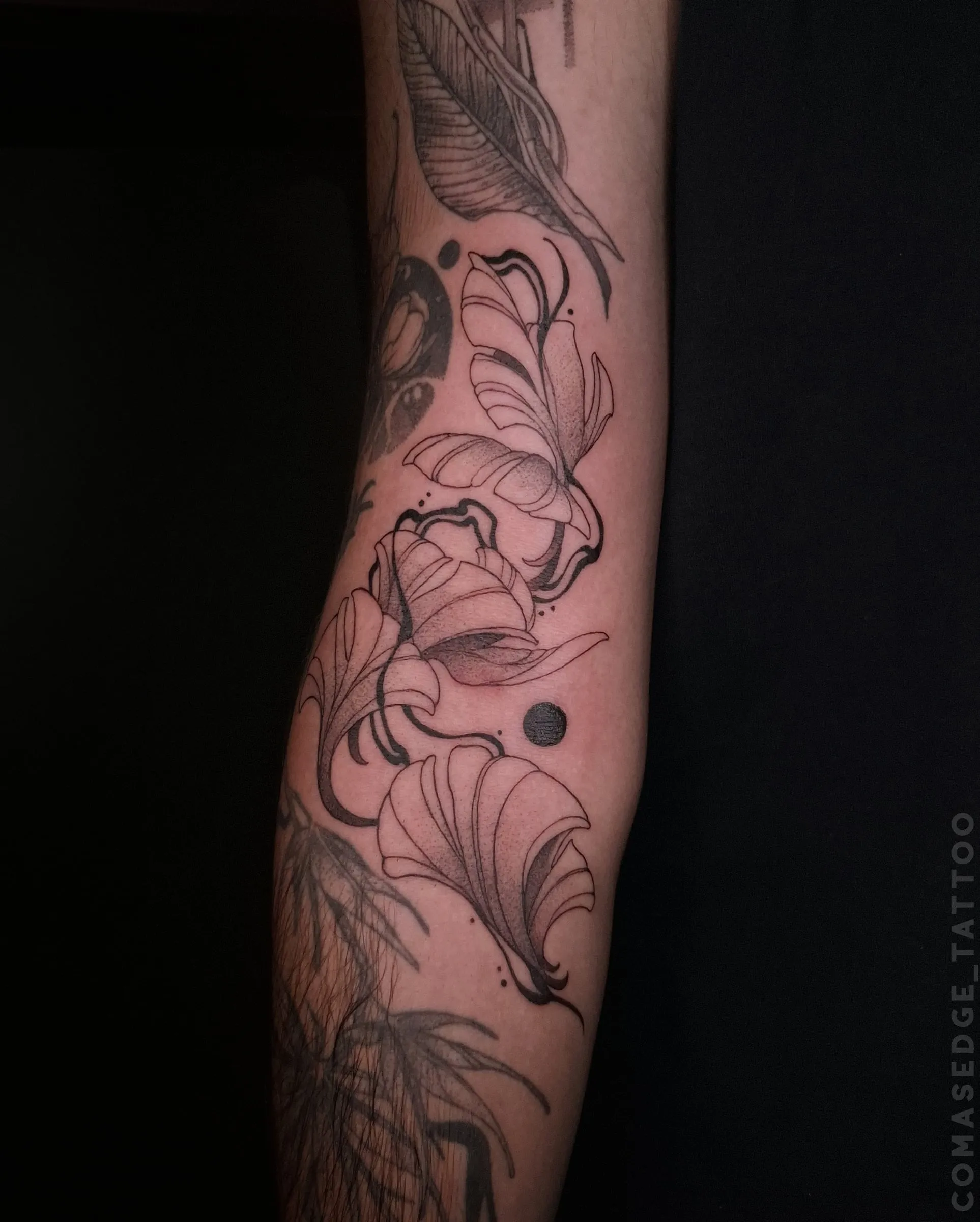 Tatouage fineline noir de plusieurs feuilles de ginkgo stylisées sur l’avant-bras, avec des courbes délicates et de petits points.