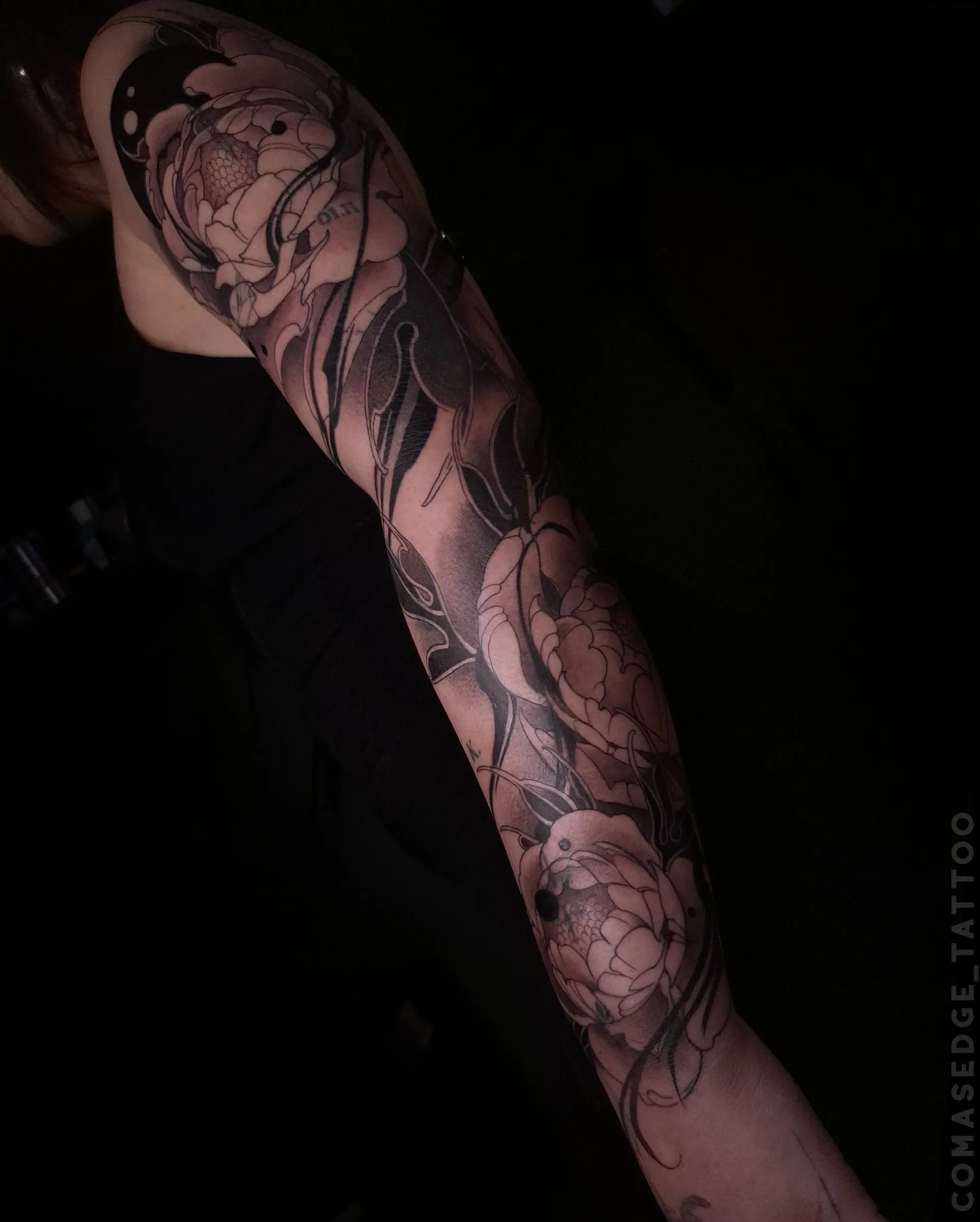 Tatouage blackwork très contrasté de trois pivoines couvrant un bras complet, sans motif animalier.