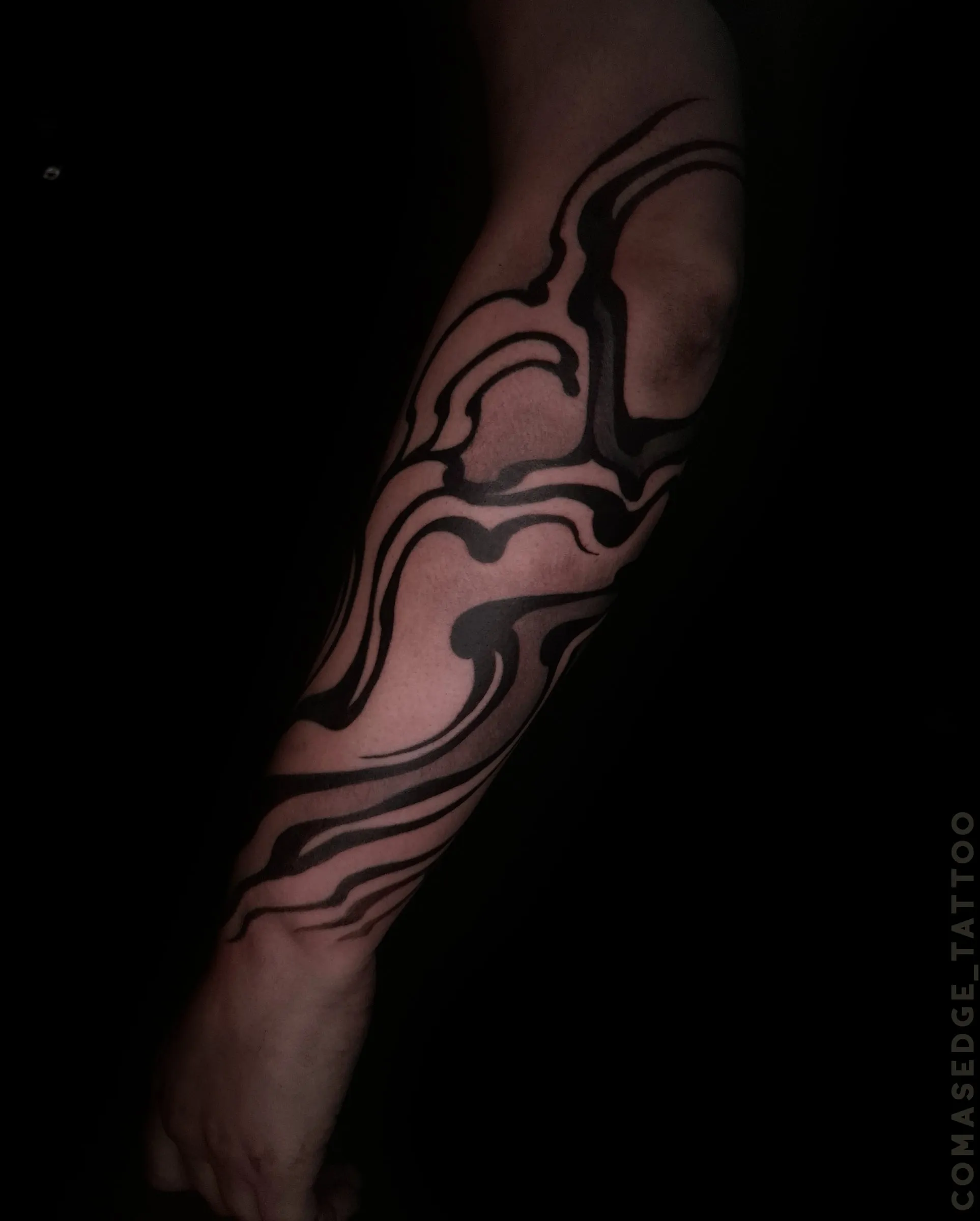 Tatouage noir d’inspiration suminagashi couvrant l’avant-bras complet, avec des courbes épaisses, fluides et vaporeuses.